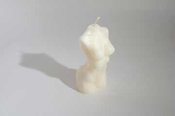 Scented candle in the shape of a female torso on a white background with a shadow