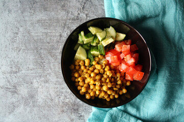 Chickpeas, tomatoes, cucumbers. Ingredients for the salad in a black bowl.