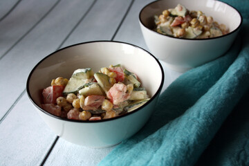 Chickpeas, tomatoes, cucumbers. Salad in a white bowl.