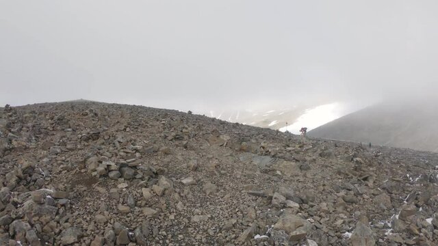 Hiker walking on a path with small rocks in foggy weather. On his way up the Kebnekaise mountain.