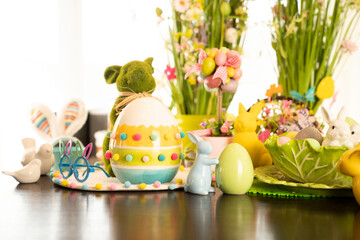 Obraz na płótnie Canvas Easter decorations in the house. Easter bunny, easter eggs in basket and cabbage leaf. Bouquets of spring flowers. 