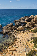 Fototapeta na wymiar Rocks and blue water on a warm fall day in Prajjet Bay or Anchor Bay, Malta.
