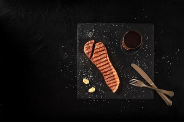 Cooked strip steak, cut, shot from above on a black background