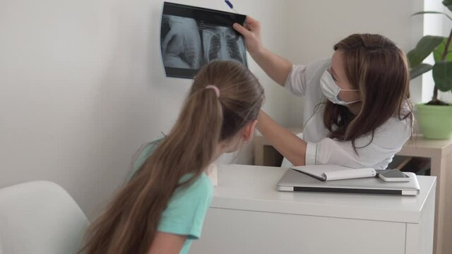 The girl at the teen's appointment at the doctor looks at a picture of her lungs, the girl has healthed the lungs clean.