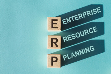 Wooden cubes building word ERP - (abbreviation Enterprise Resource Planning) on light blue background.