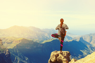 Young woman practices yoga against the backdrop of mountains and sunrise. Healthy lifestyle. Sport.