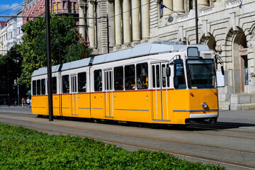 Historic yellow tram for passengers driving through the streets and part of the public transport system in in the old center in a sunny summer day.