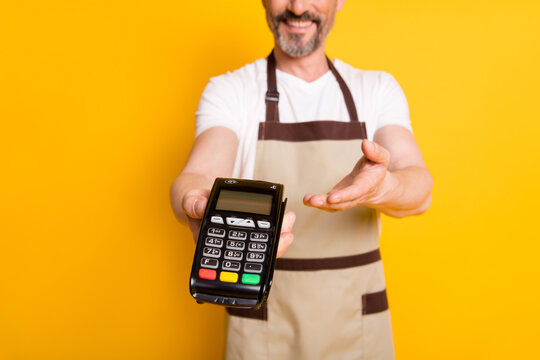 Cropped photo of cheerful assistant give you card reader wear white t-shirt apron isolated yellow background