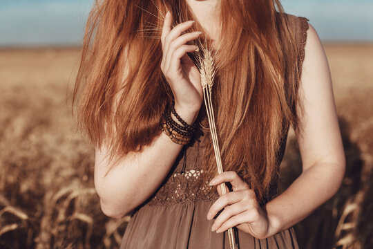 Young ginger woman in the wheat field looking relaxed.