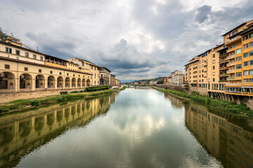 Florence. Arno River view from the Medieval Ponte Vecchio (Old Bridge). On the left the Vasari Corridor (Corridoio Vasariano, 1565), which connects Palazzo Vecchio with Palazzo Pitti. Tuscany Italy.