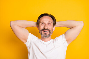 Fototapeta na wymiar Portrait of attractive cheerful virile guy looking up copy space resting isolated over bright yellow color background
