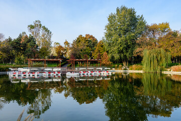 Naklejka premium Landscape with the lake and green and yellow trees in Drumul Taberei Park, also known as Moghioros Park, in Bucharest, Romania, at sunrise in an autumn morning.