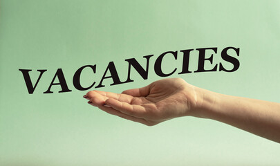 VACANCIES - word on a woman's hand on a mint background