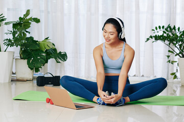 Young woman following tutorial on butterfly stretch exercise that relaxes tensed tissues and...