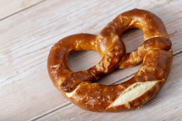 Traditional salty bavarian  bread pretzel closeup on rustic wooden background. Top view with copy space