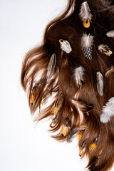 Naklejka premium Mottled feathers in long women's hair on a white background close-up