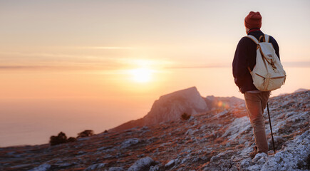 A man on top of a cliff in the spring mountains at sunset and enjoying the view of nature