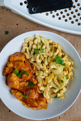 Spaetzle or Spätzle egg noodle pasta with chicken, onions and seasoning. Traditional European cuisine dish (Swabian, German, Austrian, Hungarian). Gluten free Knöpfle bowl with a grater in background.