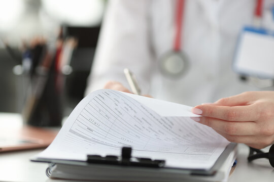 Doctor filling out medical documents in clinic closeup