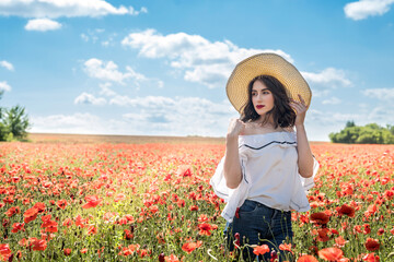 beautiful young  woman in a straw hat in a poppy field at summertime
