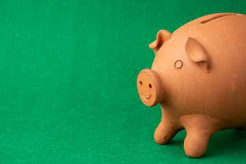 Close-up of half clay piggy bank, green background, horizontal, with copy space