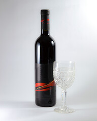 Black bottle of red wine and glass, bordolese conical, still life on a white background.