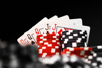 Poker chips and playing cards on black background