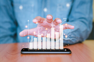 Businessman used a smartphone and touch the screen with business graph pop up on smart phone. The concept of finance and technology.