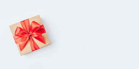Cardboard gift box with red bow on white background. Flat lay. Top view. Copy space for your text.