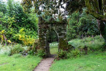 Old stone entrance gate in the garden. Fence with metal doors. Ireland
