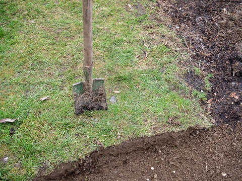 Wiese wird mit einem Spaten abgestochen