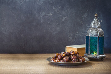 Lightened lantern and dates fruit on wooden table over dark background. Ramadan kareem holiday celebration concept