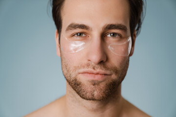 Naklejka premium Shirtless white man with under eye patches looking at camera