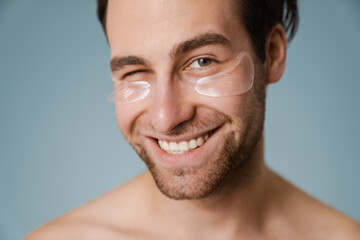 Shirtless white man with under eye patches winking at camera