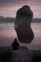 Ein Mann sitzt am See beim Sonnenaufgang