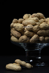 Peanuts on a black background. Glass with peanuts on a dark background. Beer snack.