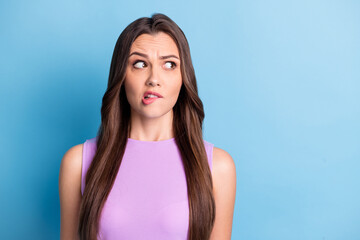 Photo portrait of brunette with doubt clueless misunderstanding face biting lip isolated on vibrant blue color background
