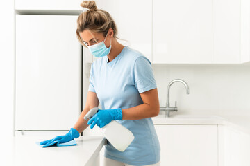 Woman worker wearing prevention mask and gloves during apartment cleaning