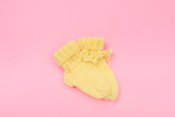 knitted baby booties on pastel pink background.