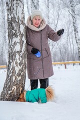 Portrait of an elderly woman with a dog. Woman with pekingese dog walking on the snowy field.