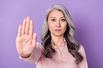 Portrait of attractive trendy elderly retired pensioner woman showing palm stop ban veto isolated...