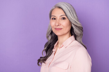 Profile side view portrait of attractive content wise grey-haired woman granny wearing pink shirt isolated over violet purple color background