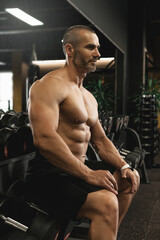 Fototapeta na wymiar Muscular bodybuilder in a free weights zone in the gym