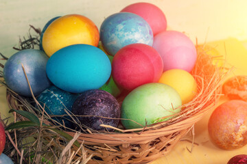 Fototapeta na wymiar Colorful easter eggs in a basket on a yellow wooden table