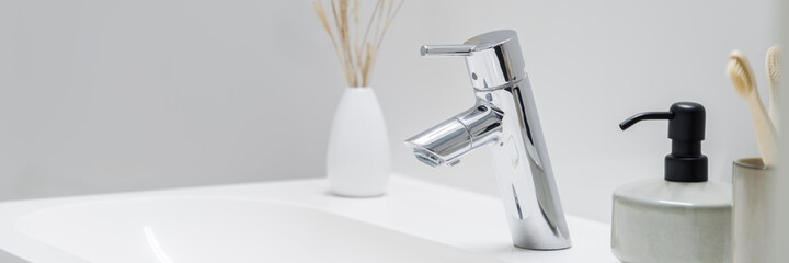 Silver tap in bathroom washbasin, panoramic close-up
