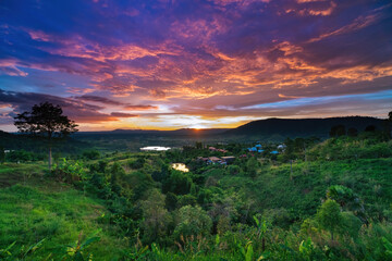 photo of colorful twilight sunset sky at mountian's hills with green field in forground