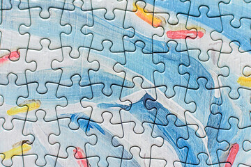 Many light grey and blue textured cardboard puzzle pieces on a table, weekend indoor activity for playing with children at home.