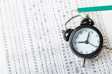 alarm clock, optical form of standardized school test with bubble and black pencil, answer sheet, education concept