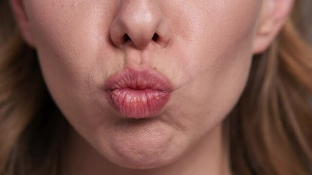 A close-up cropped view of a woman is sending an air kiss to the camera