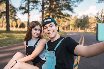 Fototapeta premium A couple of teenage lovers taking a selfie in a park.